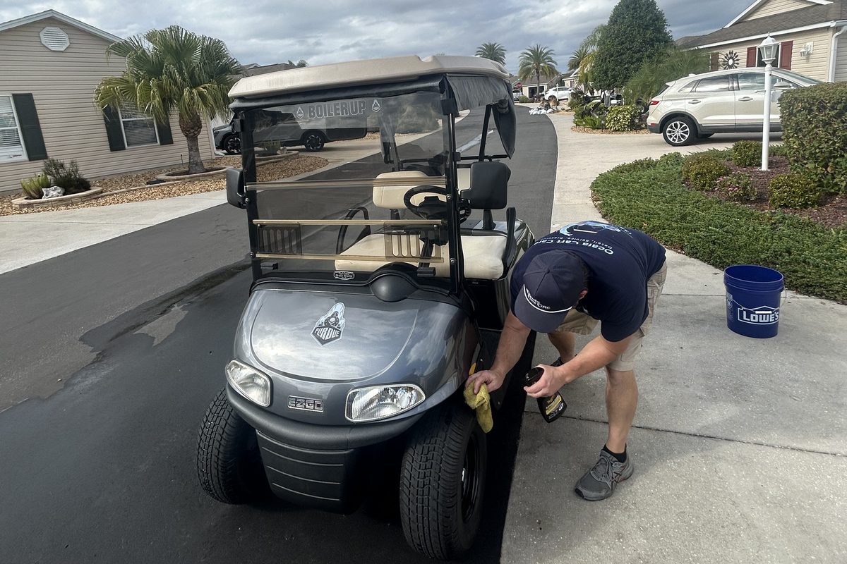 Ocala Cart Care technician detailing a golf cart in a customer driveway