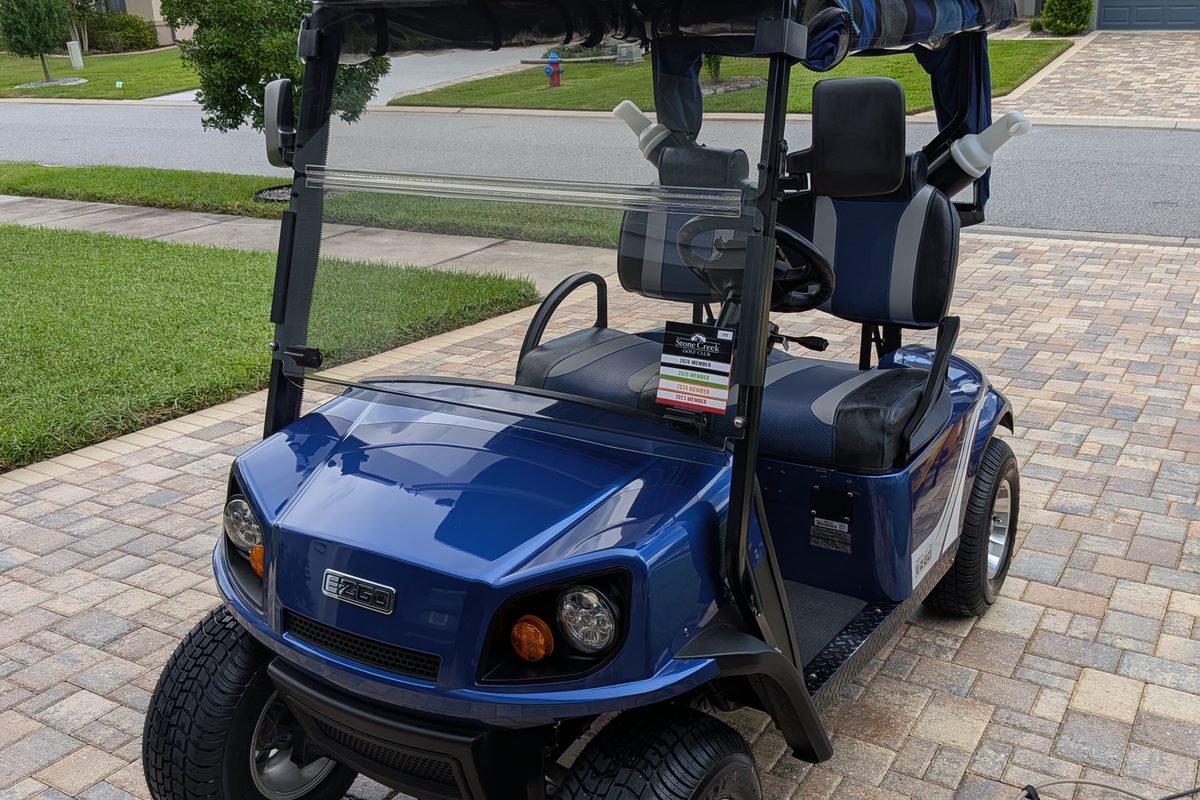 Clean blue EZGO golf cart on a paver driveway after a Care Plan visit