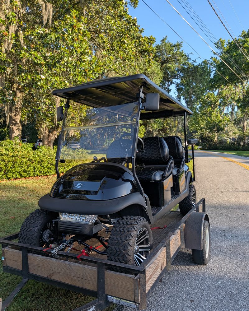 Lifted black golf cart strapped down on a trailer, ready for transport in Ocala, FL